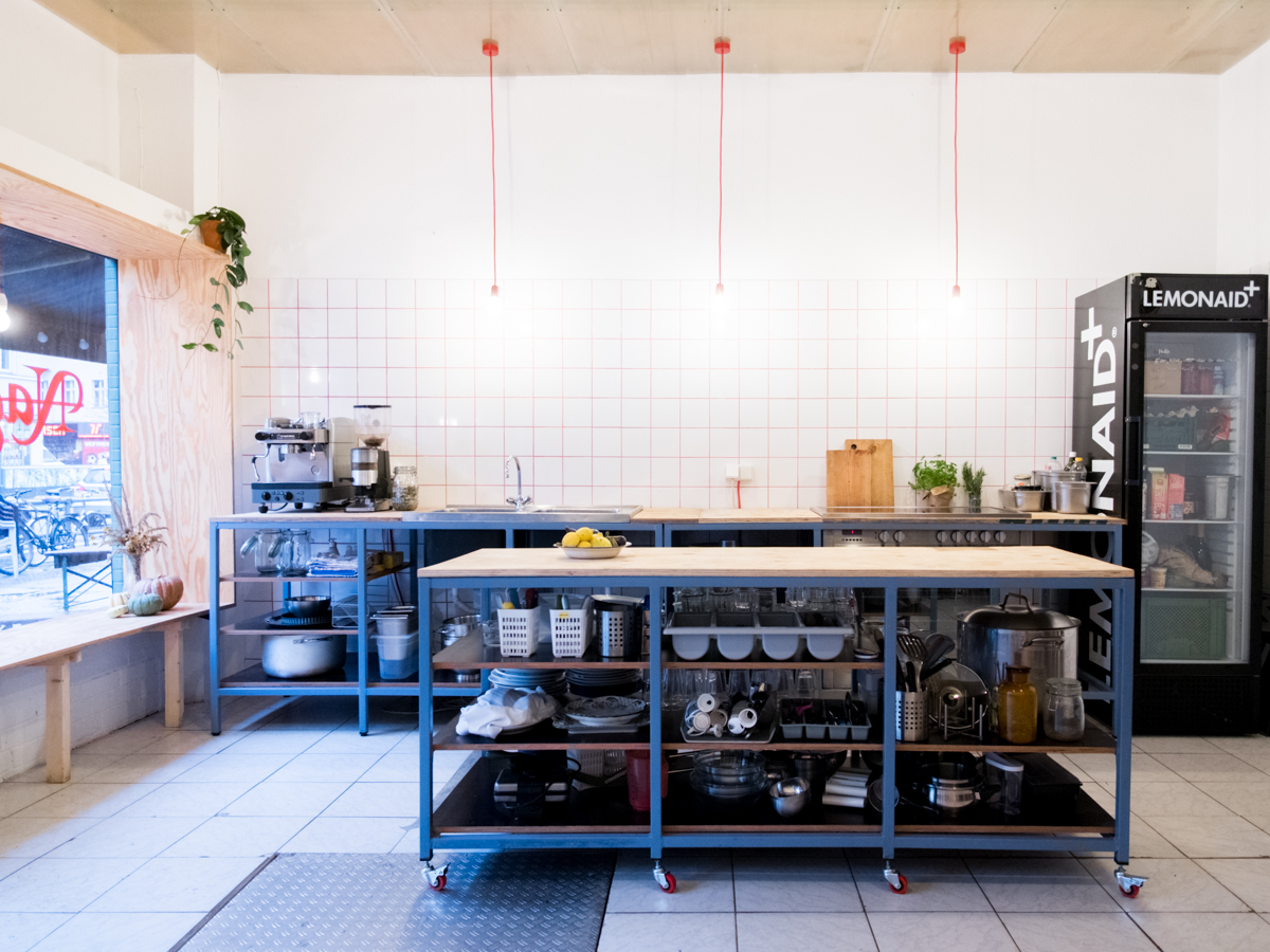 Blick in Küche aus blauem Stahl, drei Lampen hängen von der Decke.
